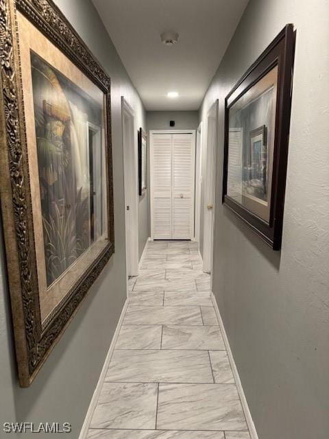 corridor featuring marble finish floor and baseboards