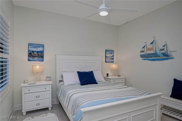 bedroom with ceiling fan, light wood-style floors, and baseboards