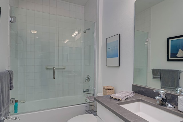 bathroom featuring toilet, combined bath / shower with glass door, and vanity