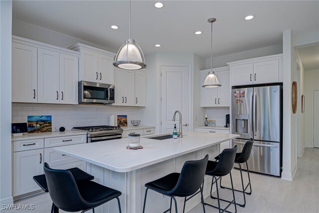 kitchen with appliances with stainless steel finishes, a sink, a breakfast bar, and white cabinetry