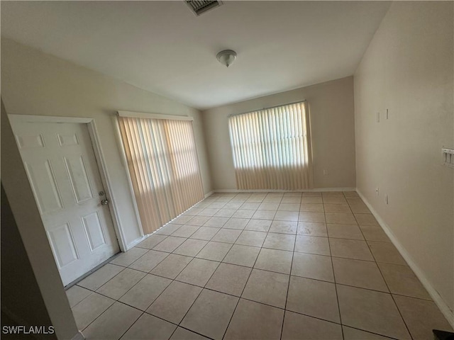 unfurnished room with visible vents, vaulted ceiling, baseboards, and light tile patterned floors