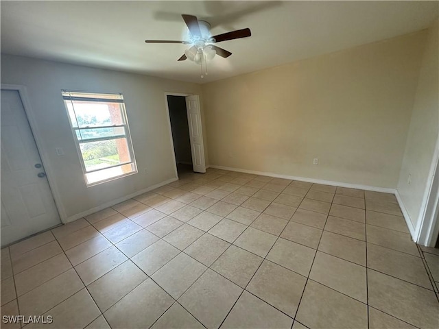 empty room featuring ceiling fan, baseboards, and light tile patterned floors