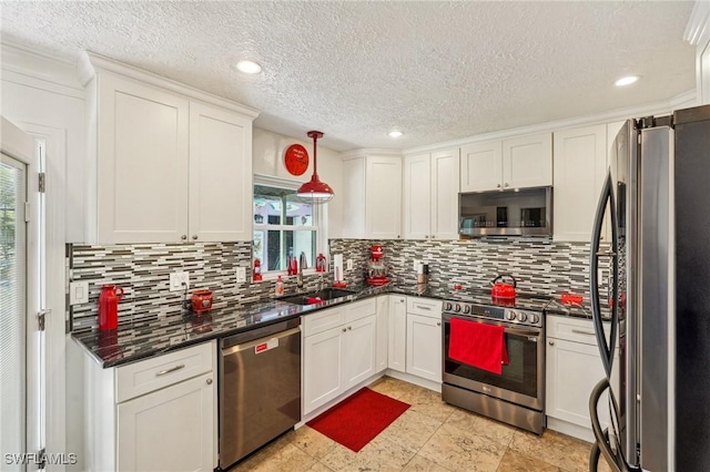 kitchen featuring appliances with stainless steel finishes, white cabinetry, a sink, and decorative backsplash