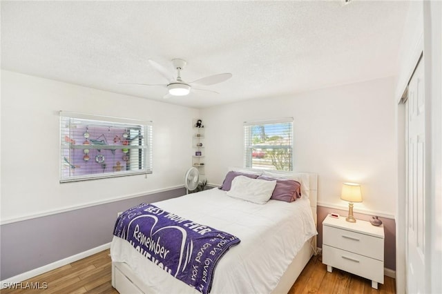 bedroom featuring baseboards, a ceiling fan, light wood-style flooring, a textured ceiling, and a closet