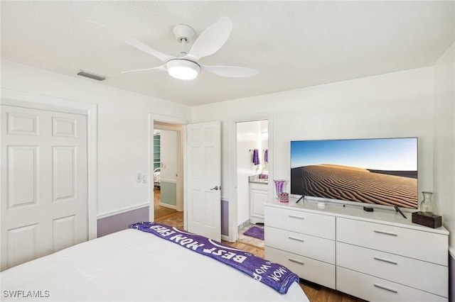 bedroom featuring a ceiling fan, visible vents, connected bathroom, and wood finished floors