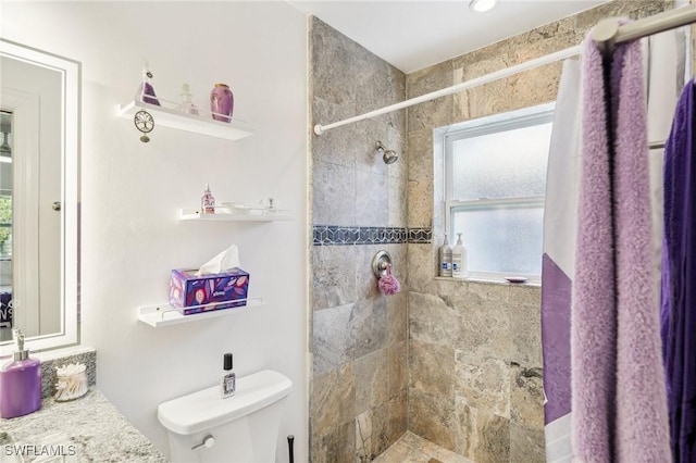 bathroom featuring tiled shower, vanity, and toilet