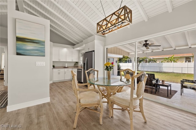 dining space with light wood-style flooring, baseboards, and beamed ceiling