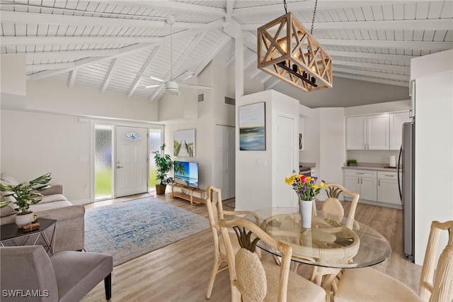 dining room featuring light wood-style floors, visible vents, and beamed ceiling