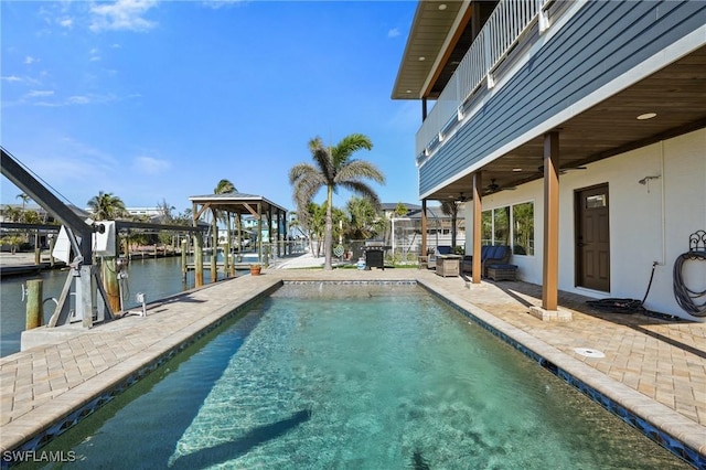 outdoor pool with a water view, a patio area, boat lift, a ceiling fan, and a boat dock