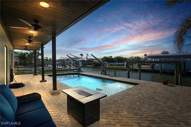 outdoor pool featuring a patio, a ceiling fan, a boat dock, a water view, and boat lift