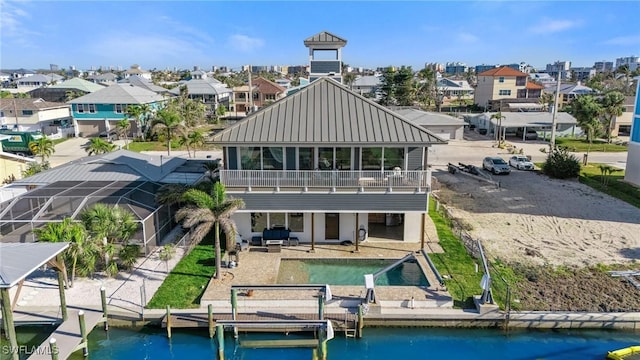 back of house with metal roof, a water view, a patio, and a residential view