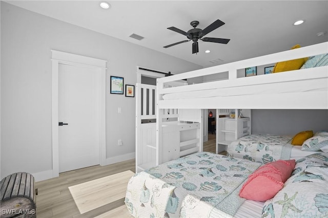 bedroom with wood finished floors, visible vents, baseboards, recessed lighting, and a barn door