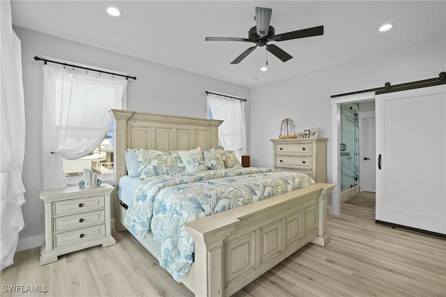 bedroom featuring a barn door, recessed lighting, light wood-type flooring, and baseboards