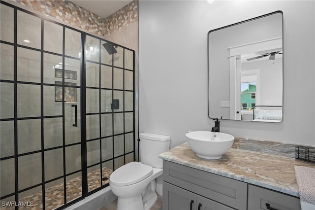 bathroom with vanity, toilet, a tile shower, and ceiling fan