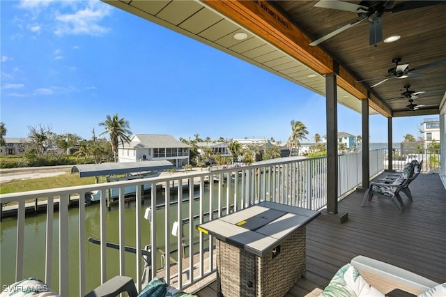 balcony with a ceiling fan, a water view, and a residential view