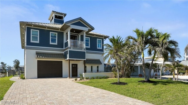 view of front of home featuring a balcony, a front lawn, a garage, decorative driveway, and metal roof