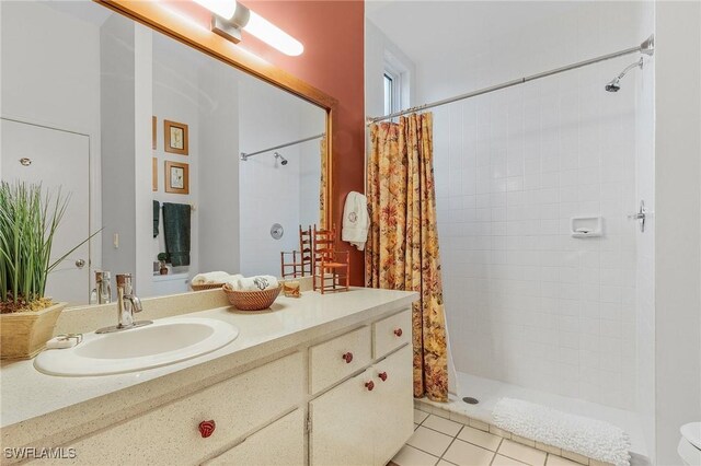 bathroom with tiled shower, tile patterned flooring, and vanity