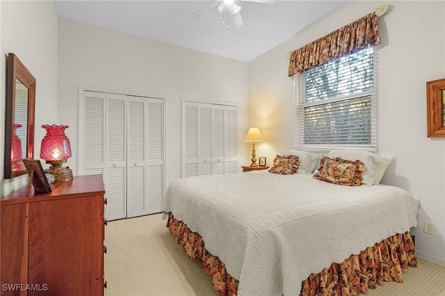 bedroom featuring light carpet, ceiling fan, and multiple closets