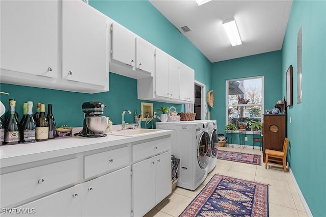 laundry room featuring light tile patterned floors, cabinet space, visible vents, washing machine and dryer, and a sink