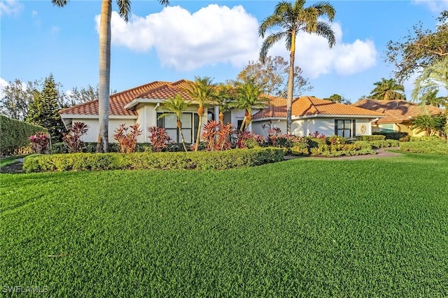 view of front of house featuring an attached garage, a front yard, a tile roof, and stucco siding