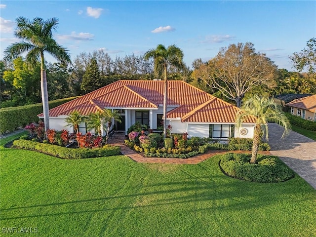 view of front of house with a tiled roof, decorative driveway, and a front yard