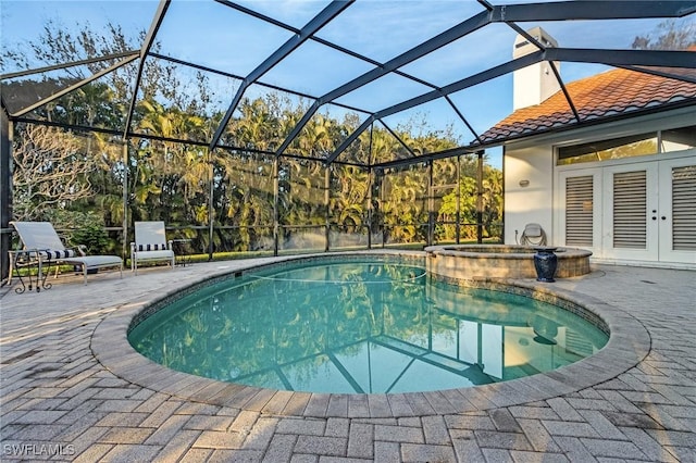 view of swimming pool with glass enclosure, a pool with connected hot tub, a patio, and french doors