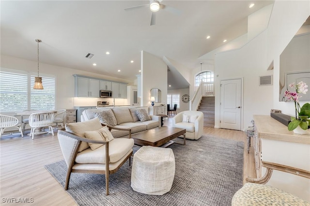 living area with stairs, light wood-style flooring, plenty of natural light, and visible vents