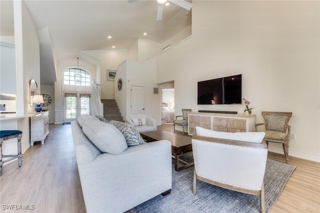 living area featuring light wood finished floors, ceiling fan, a high ceiling, french doors, and recessed lighting