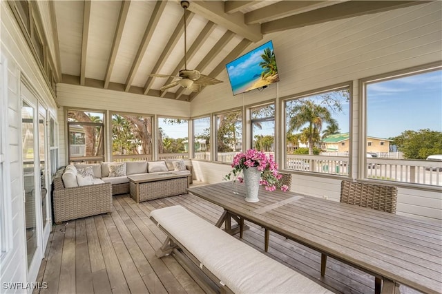 sunroom featuring lofted ceiling with beams, ceiling fan, and plenty of natural light