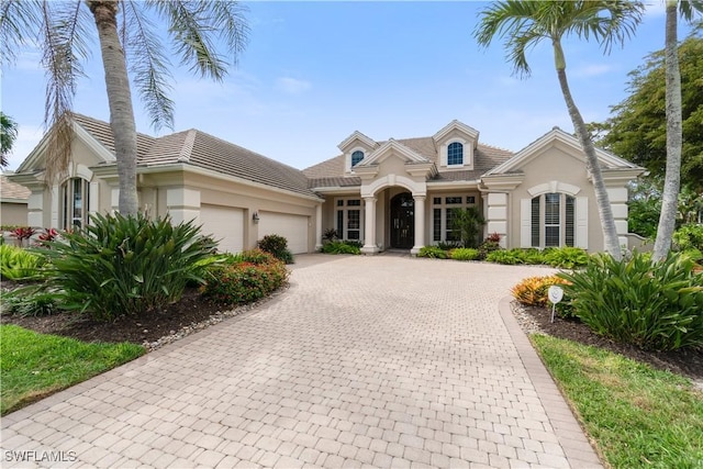 view of front facade featuring a garage, decorative driveway, and stucco siding