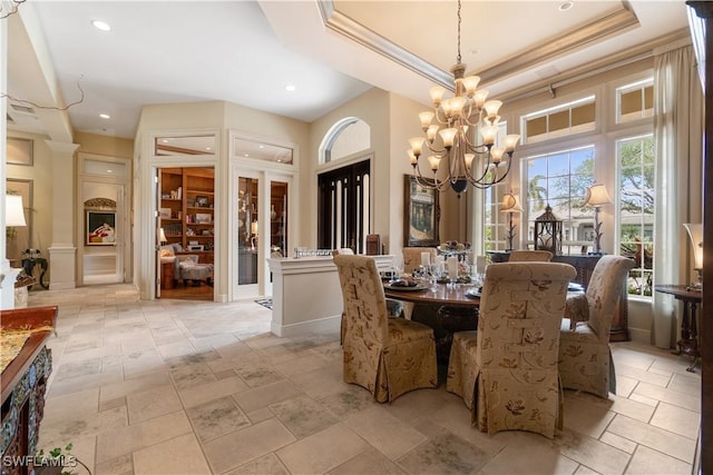 dining room with an inviting chandelier, baseboards, a raised ceiling, and crown molding