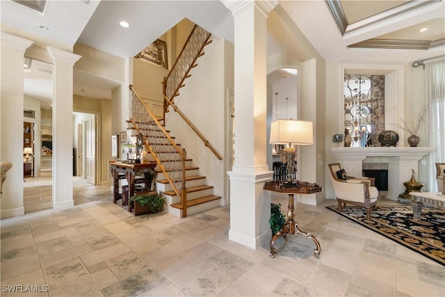 entrance foyer featuring stairway, a fireplace, decorative columns, and baseboards