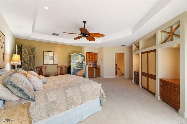 bedroom with visible vents, a tray ceiling, baseboards, and light colored carpet