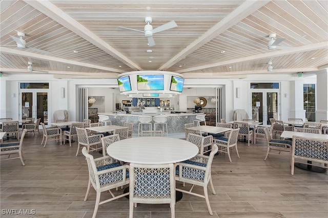 dining space with ceiling fan, wood tiled floor, beam ceiling, and french doors