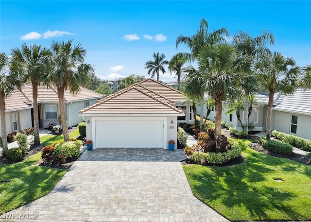 ranch-style house featuring a garage, a tiled roof, decorative driveway, stucco siding, and a front yard