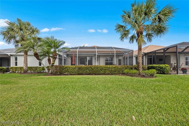 back of property featuring a lanai and a lawn