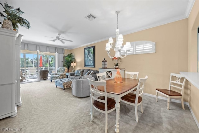 carpeted dining space featuring ornamental molding, visible vents, baseboards, and ceiling fan with notable chandelier