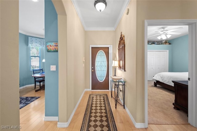 entryway featuring light wood-type flooring, baseboards, ornamental molding, and arched walkways