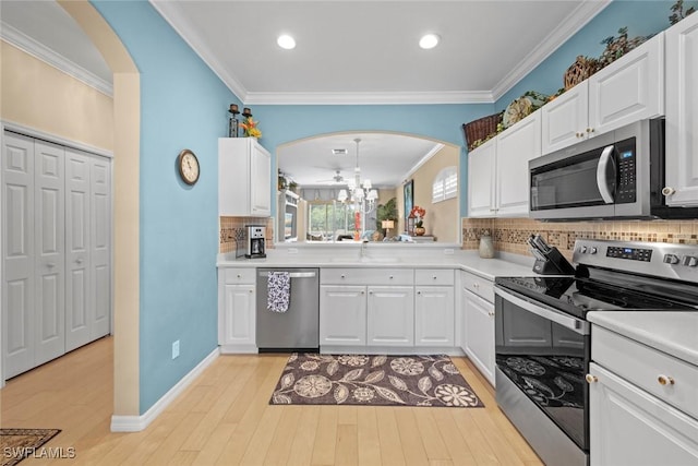 kitchen featuring appliances with stainless steel finishes, light wood-type flooring, and crown molding