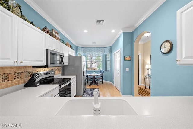 kitchen with arched walkways, stainless steel appliances, light countertops, visible vents, and ornamental molding