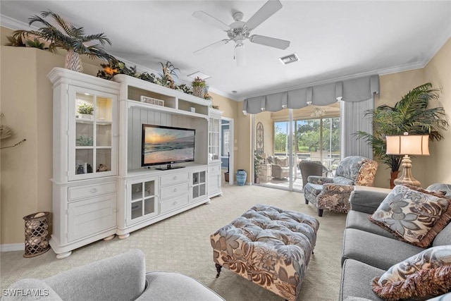 living room with ornamental molding, a ceiling fan, visible vents, and light colored carpet