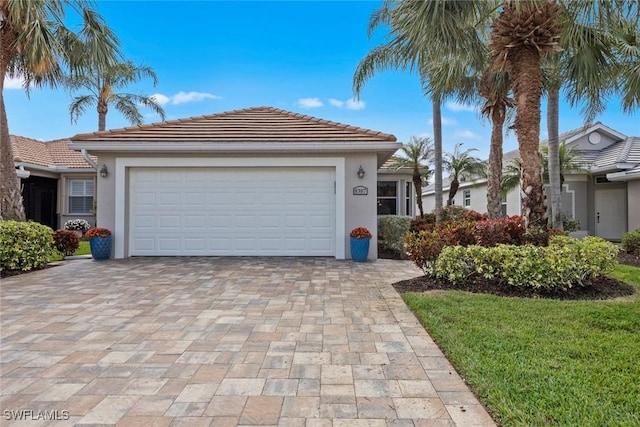 exterior space with a tiled roof, decorative driveway, an attached garage, and stucco siding