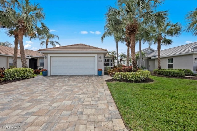 ranch-style home featuring decorative driveway, stucco siding, an attached garage, a front yard, and a tiled roof