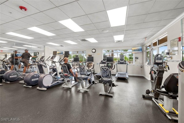 workout area featuring a paneled ceiling and baseboards