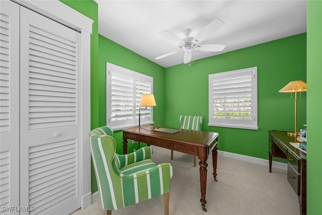 carpeted office space featuring baseboards and ceiling fan