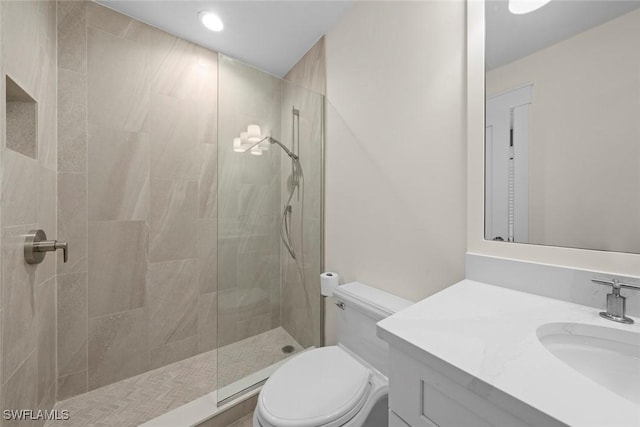 bathroom with vanity, toilet, and a tile shower