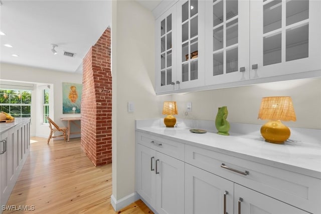 bar featuring visible vents, light wood-style flooring, and baseboards