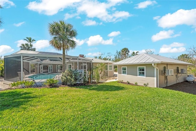 rear view of house with a lanai, metal roof, a yard, an outdoor pool, and a standing seam roof