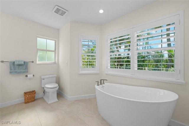 bathroom with baseboards, visible vents, recessed lighting, a freestanding bath, and toilet