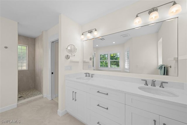 full bathroom with a sink, baseboards, double vanity, and a tile shower